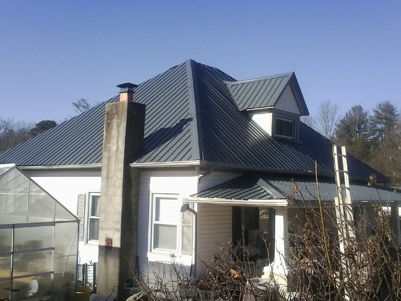 Dark blue standing seam metal roof on a white farmhouse with dormer — Slate & Tile Roof Repair by Roofing Brothers in Nicholasville