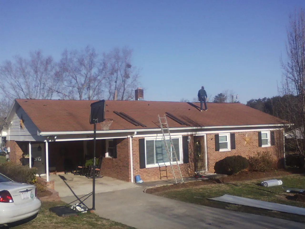 Roofer stripping a shingle roof on a brick ranch before metal panels in Nicholasville