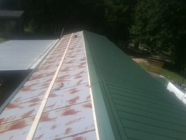 Old rusted panels beside newly installed green metal roofing — Wind Damage Roof Repair by Roofing Brothers in Nicholasville
