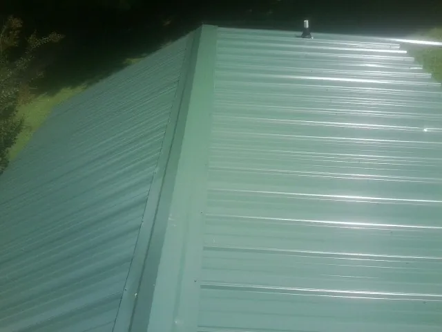 New green metal panels meeting at the ridge of a roof — Flat Roof Repair work by our crew in Nicholasville