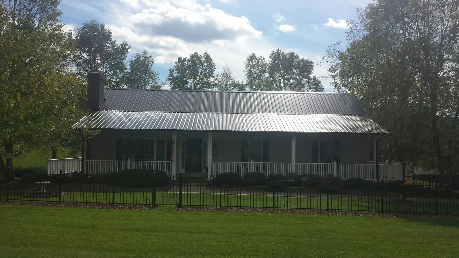 Gray metal roof on a brick ranch with a full width front porch — Gutter Guard Installation work by our crew in Nicholasville