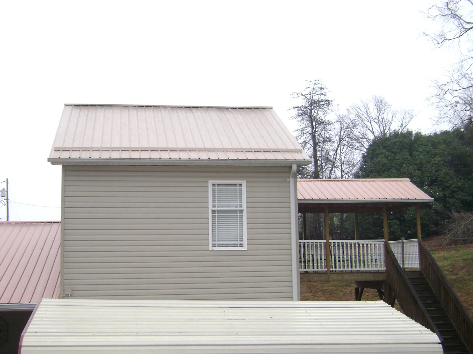 Tan metal roofs on a two story addition and attached porch, from a Roof Replacement job in Nicholasville