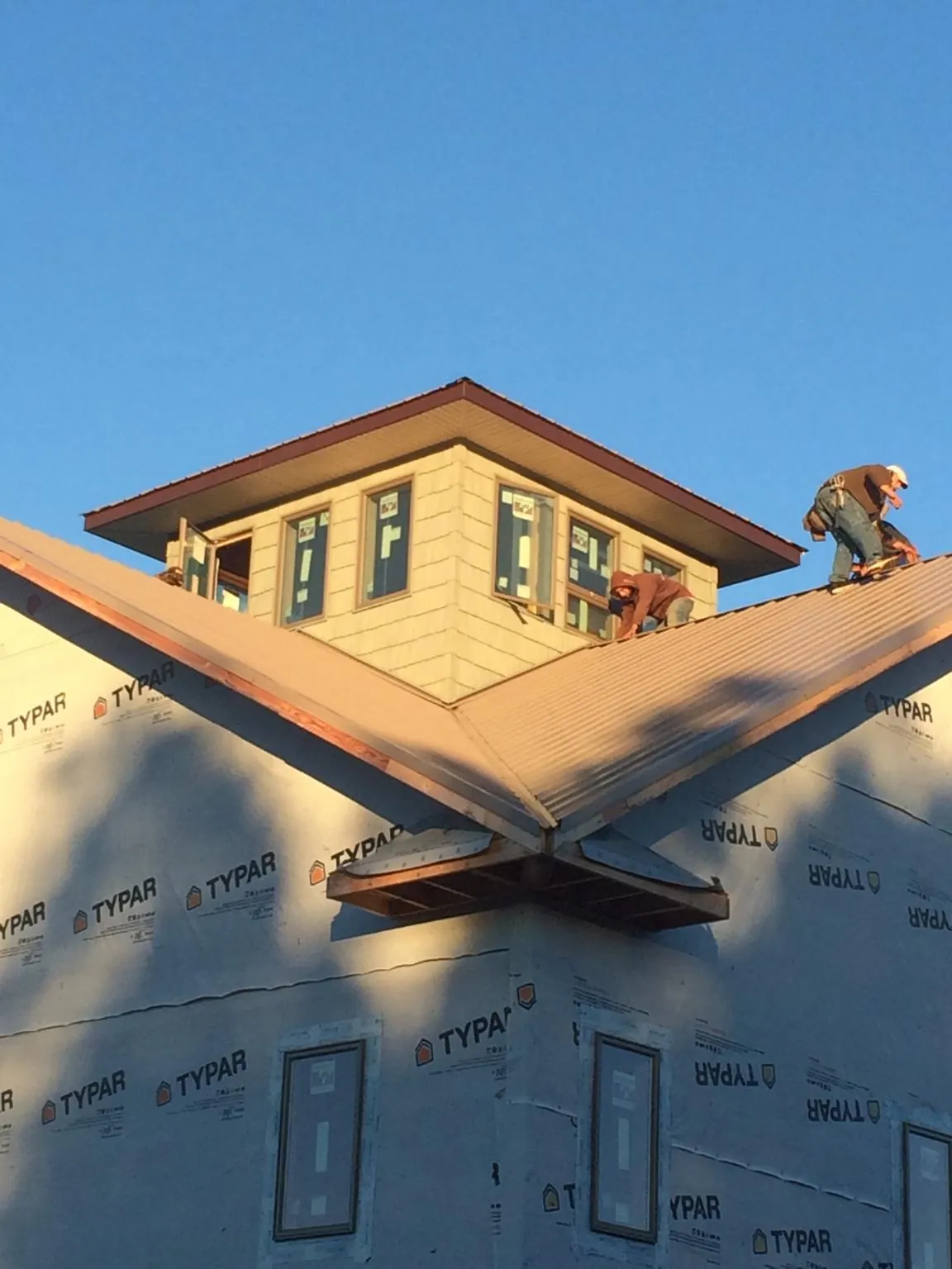Roofers working around a rooftop cupola on a new metal roof at sunset — Roof Waterproofing in Nicholasville by Roofing Brothers